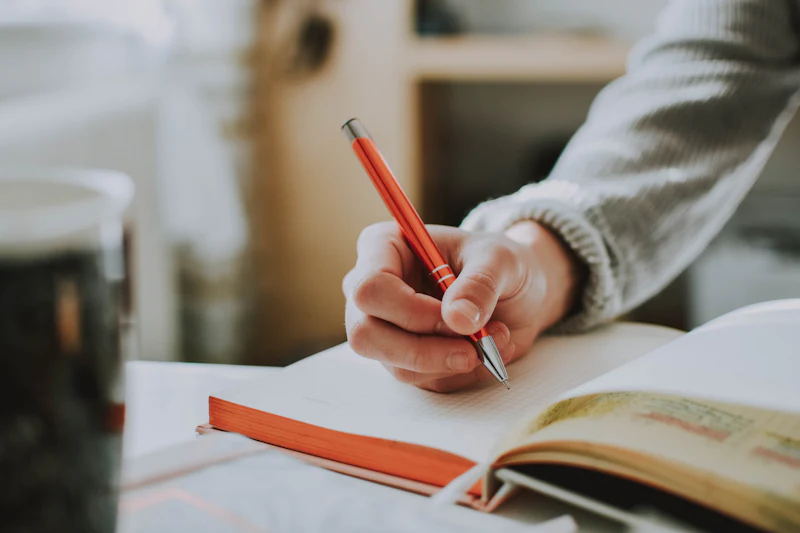 Hand writing notes in a notebook with a pen